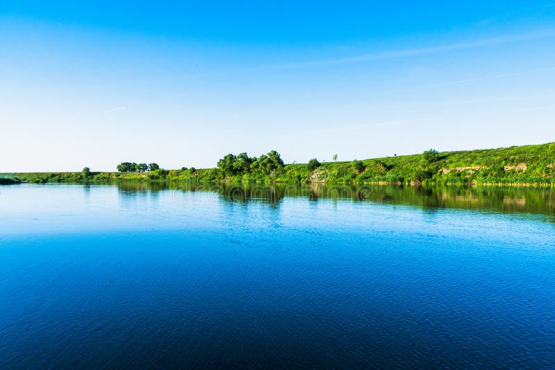 Bright summer nature panorama, forest trees and river with reflection in water, vivid tranquil and relax background royalty free stock photos