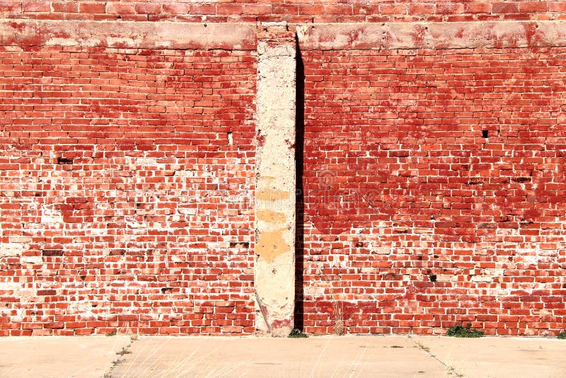 A bright sunlit vintage red brick building wall and sidewalk with shadows