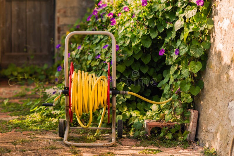 Watering garden hose near old stone house