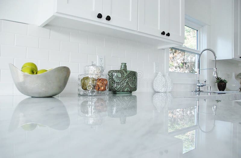 Cucina bianca con ripiani in marmo di carrara e rubinetto cromato.