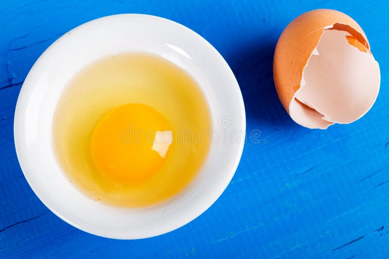 Bright Yellow Egg Yolk In White Bowl On Old Wooden Table Stock Photo