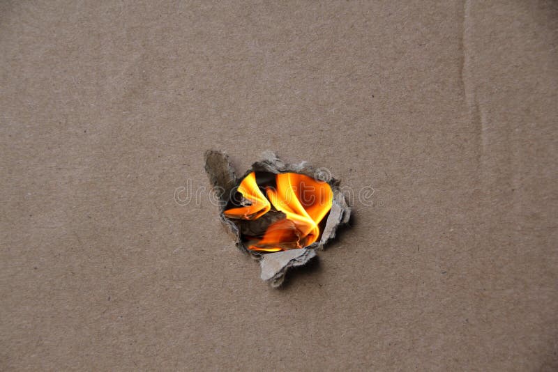 Bright Yellow Flame of Fire in the Torn Hole of Gray Rough Cardboard As
