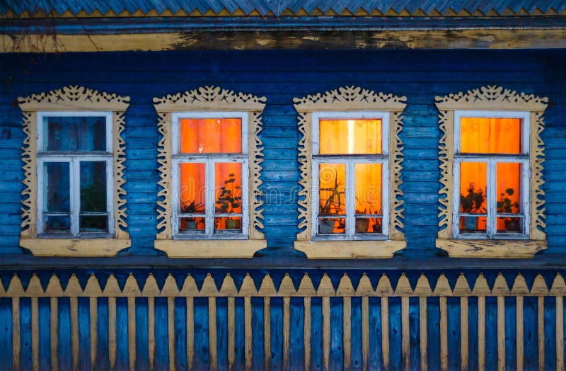 Bright yellow lighting carved windows of rural log house in the village. Bright yellow lighting carved windows of rural log house in the village