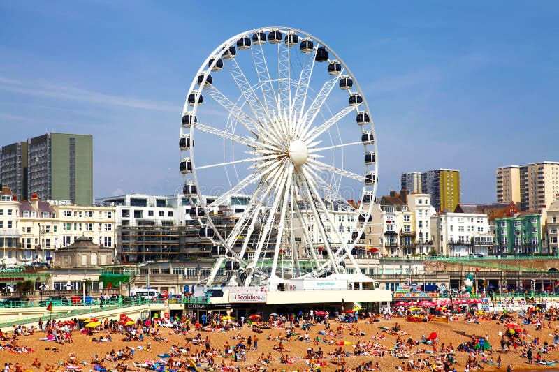 BRIGHTON -JULY 14 - View the golden sand of Brighton beachfront to the ferris wheel and amusement park with groups of people on th