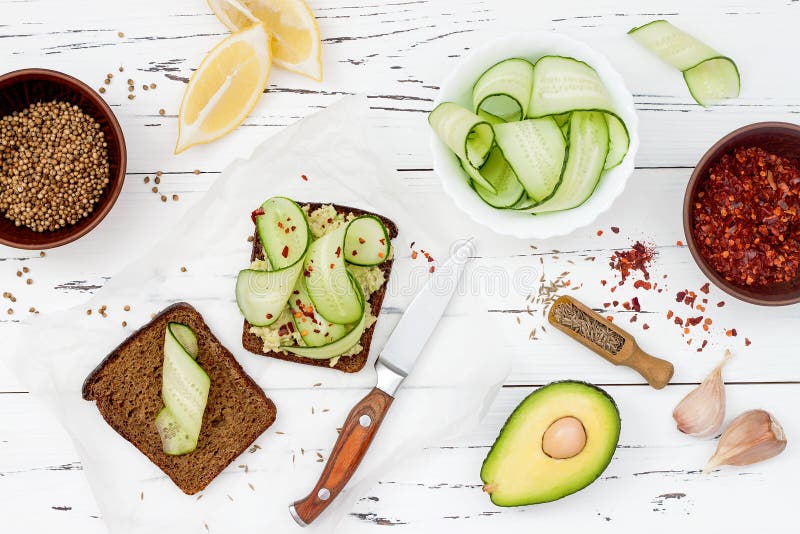 Brinde de Holewheat com fatias do guacamole e do pepino do abacate Tome o café da manhã com os sanduíches picantes do abacate no fotos de stock Brinde de Holewheat com fatias do guacamole e do pepino do abacate Tome o café da manhã com os sanduíches picantes do abacate no fotos de stock