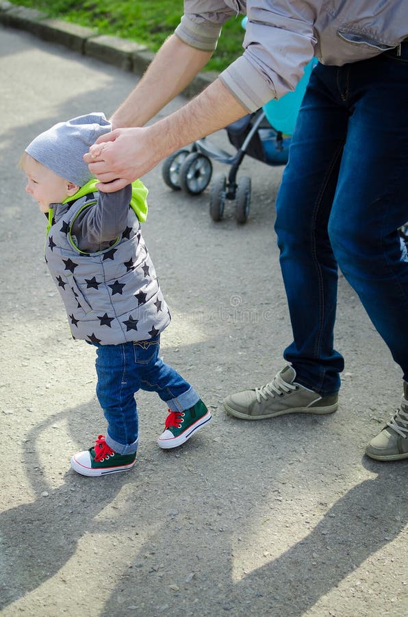Bringen Sie das Führen seines Babys mit den ersten Schritten hervor lizenzfreie stockbilder
