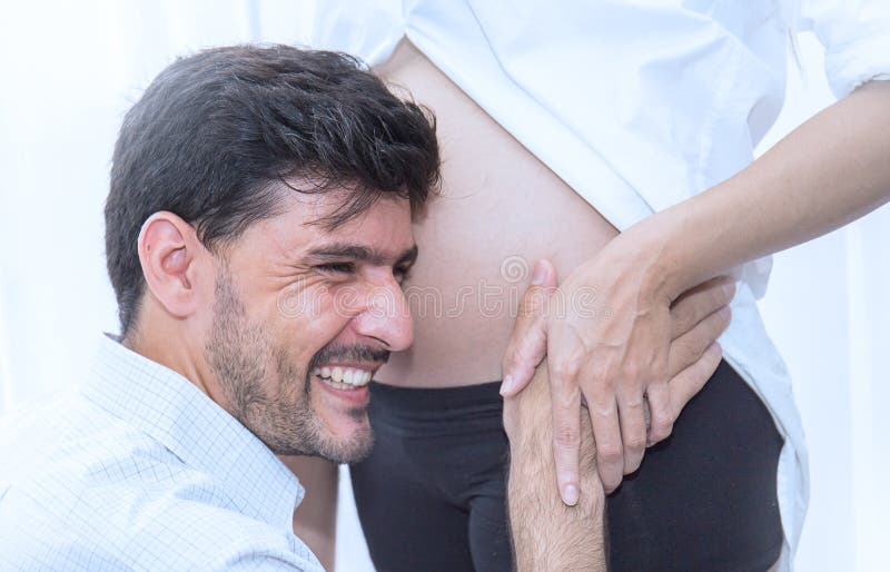 Bringen Sie das Küssen seines schwangeren Frau ` s Bauches hervor stockbild Bringen Sie das Küssen seines schwangeren Frau ` s Bauches hervor stockbild