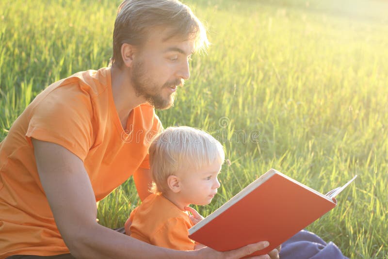 Bringen Sie und sein gelesenes Buch des Kleinkindes Sohn zusammen im Freienhervor Kopieren Sie cpace stockbilder Bringen Sie und sein gelesenes Buch des Kleinkindes Sohn zusammen im Freienhervor Kopieren Sie cpace stockbilder
