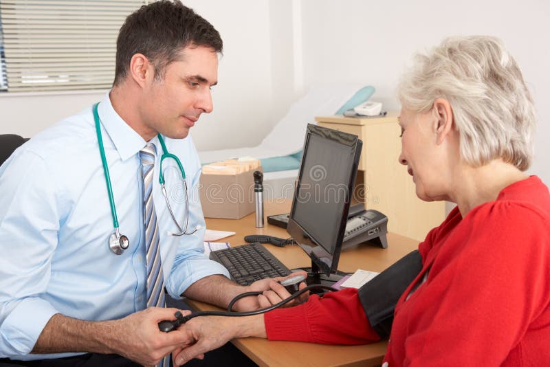 BRITISCHER Doktor, der Blutdruck der älteren Frau nimmt stockbild BRITISCHER Doktor, der Blutdruck der älteren Frau nimmt stockbild