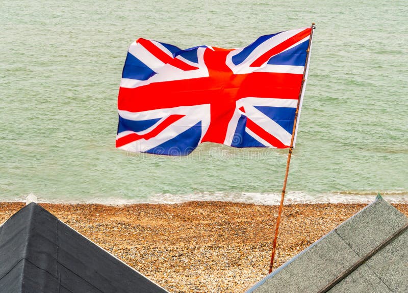 British Union Jack flag flying from a pole on beach huts at the