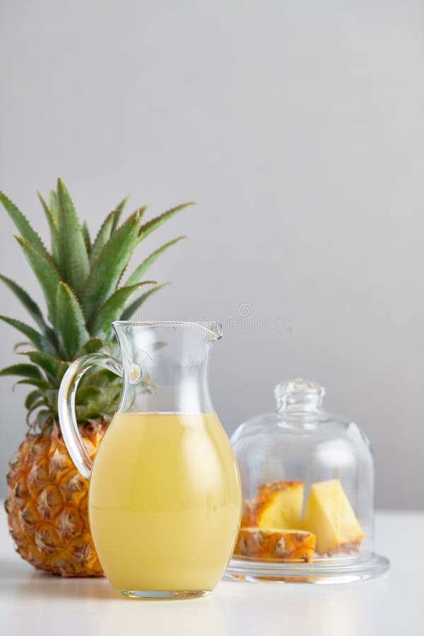 Brocca di vetro con il succo e la frutta di ananas sulla tavola immagini stock Brocca di vetro con il succo e la frutta di ananas sulla tavola immagini stock