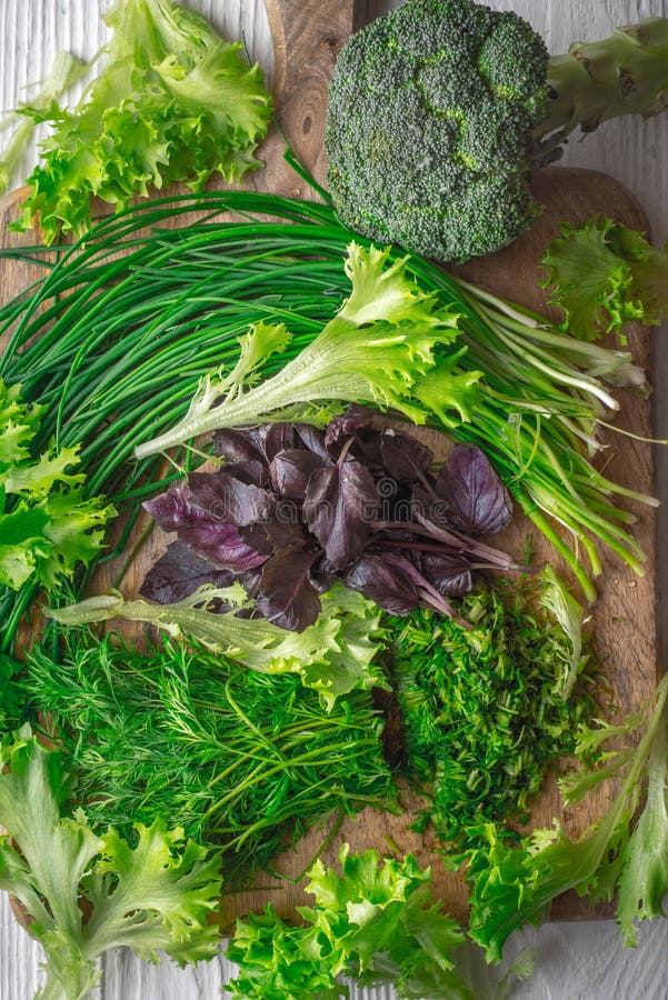 Broccoli grönsallat, basilika, lök, dill på skärbräda arkivbilder Broccoli grönsallat, basilika, lök, dill på skärbräda arkivbilder
