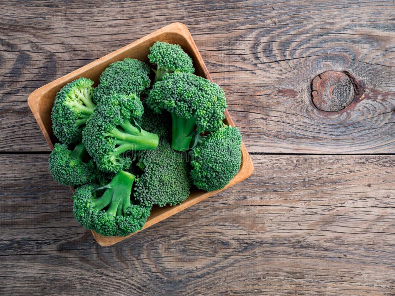 Broccoli verdi crudi freschi in ciotola di legno su fondo di legno, a fotografia stock Broccoli verdi crudi freschi in ciotola di legno su fondo di legno, a fotografia stock