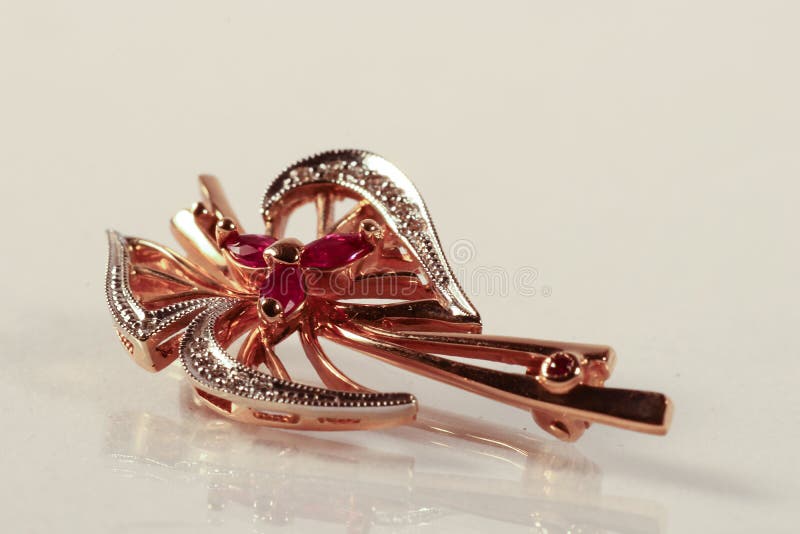 Broche d'or avec des diamants et des rubis sur le fond blanc avec du Re photographie stock libre de droits Broche d'or avec des diamants et des rubis sur le fond blanc avec du Re photographie stock libre de droits