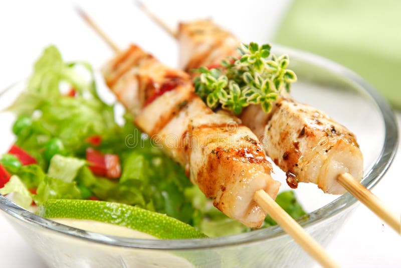 Pork (or chicken) on a grill spit with salad and a slice of lime and lemon-thyme as garnish. Pork (or chicken) on a grill spit with salad and a slice of lime and lemon-thyme as garnish