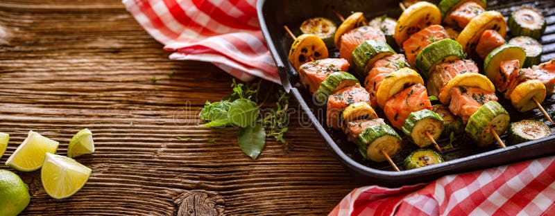 Brochettes de saumon avec la courgettes dans une casserole de grillades dans un contexte de bois image stock