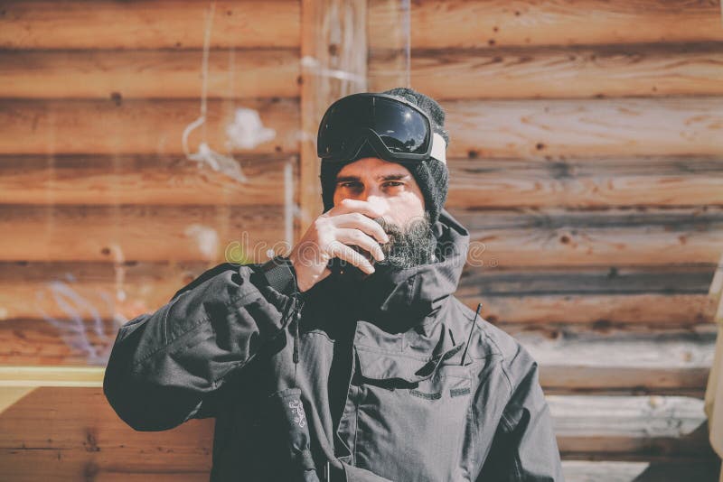 Brodaty przystojny snowboarded bierze odpoczynek po przejażdżki sesi Młody człowiek pije filiżankę gorąca herbata na pogodnym tar fotografia royalty free Brodaty przystojny snowboarded bierze odpoczynek po przejażdżki sesi Młody człowiek pije filiżankę gorąca herbata na pogodnym tar fotografia royalty free