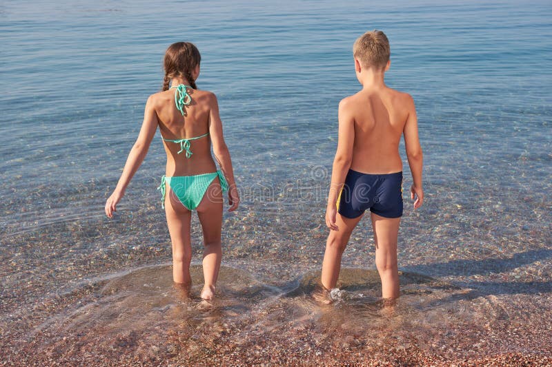 Broder och syster kommer in i ett öppet hav. Sommardag semester fotografering för bildbyråer
