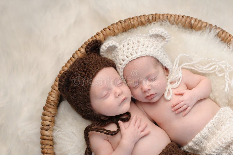 Two month old, boy and girl fraternal twin babies. They are sleeping together in a basket wearing coordinated, crocheted, bear bonnets. Two month old, boy and girl fraternal twin babies. They are sleeping together in a basket wearing coordinated, crocheted, bear bonnets.