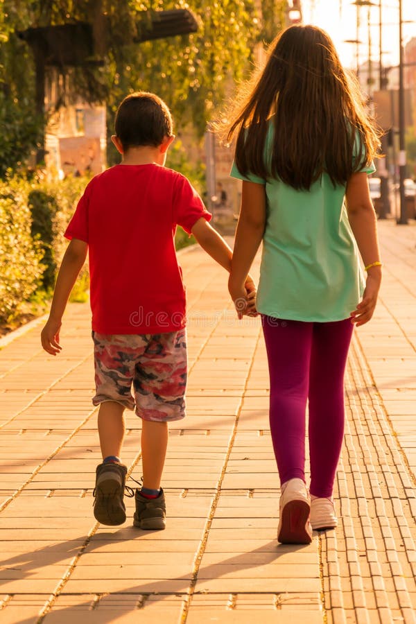 Broer en zuster die onderaan de straat lopen Zusters die handen houden royalty-vrije stock afbeelding Broer en zuster die onderaan de straat lopen Zusters die handen houden royalty-vrije stock afbeelding