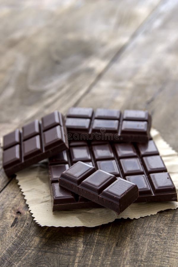 Broken chocolate bar on wooden table.