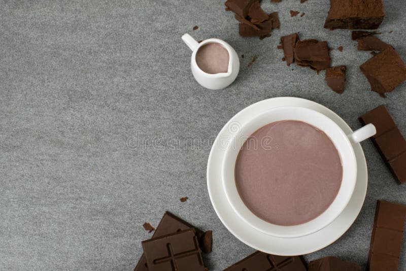 Broken chocolate with small piece and milk in glass on tile table