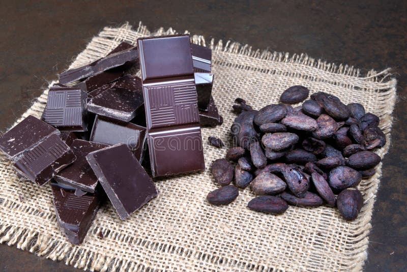 Broken dark chocolate and cocoa beans on a stone table broken dark chocolate and cocoa beans on a stone table close up stock fotografie
