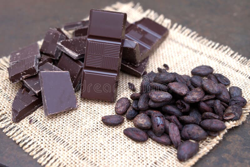 Broken dark chocolate and cocoa beans on a stone table close up broken dark chocolate and cocoa beans on a stone table royalty-vrije stock foto's