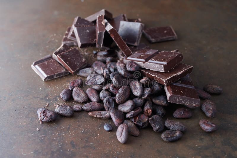 Broken dark chocolate and cocoa beans on a stone table close up broken dark chocolate and cocoa beans on a stone table stock foto's