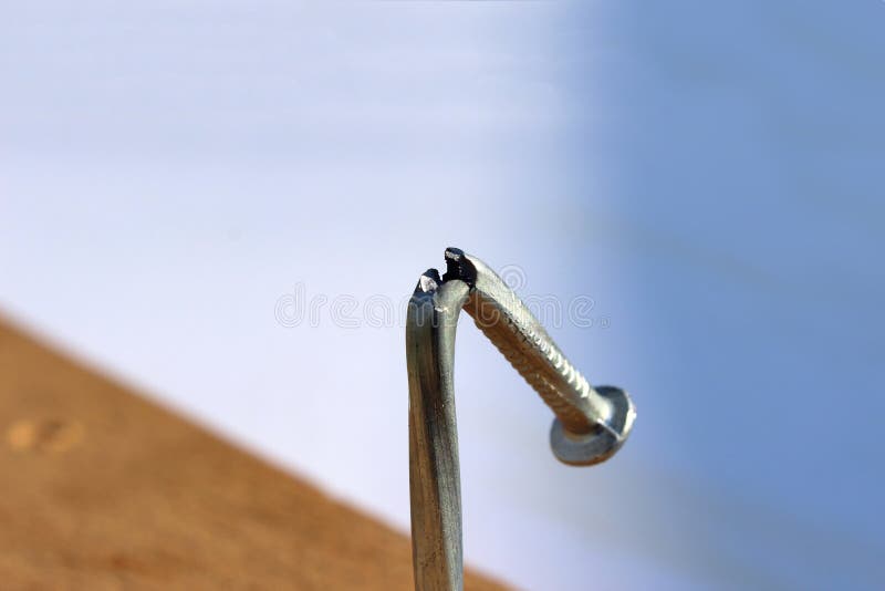 Broken and defective new metal nail closeup. Bent damaged product. Reject expendable material