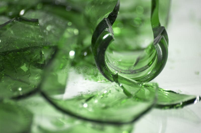 Un mucchio di cocci di vetro verde con messa a fuoco selettiva su un pezzo in mezzo.