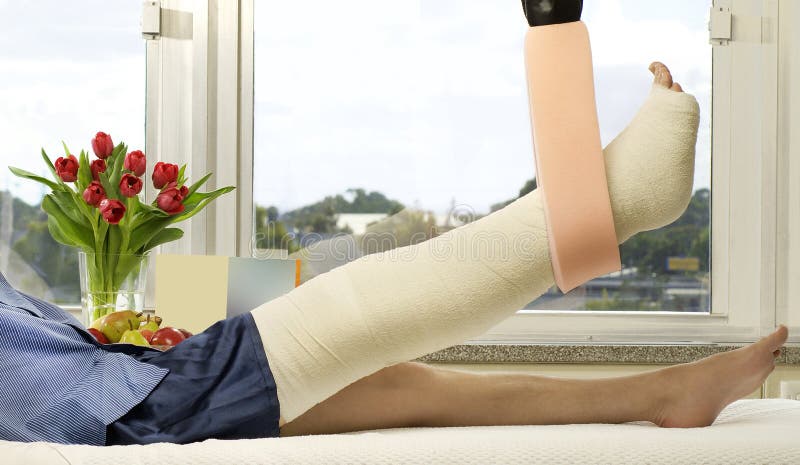 Hombre mintiendo en una cama su pierna elevado en tracción flores tarjetas próximo sobre el él.