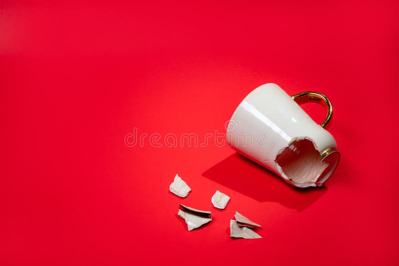 Broken Tea Cup Isolated on Red Background. Cracked Coffee Mug and Fragile Ceramic Pieces Stock