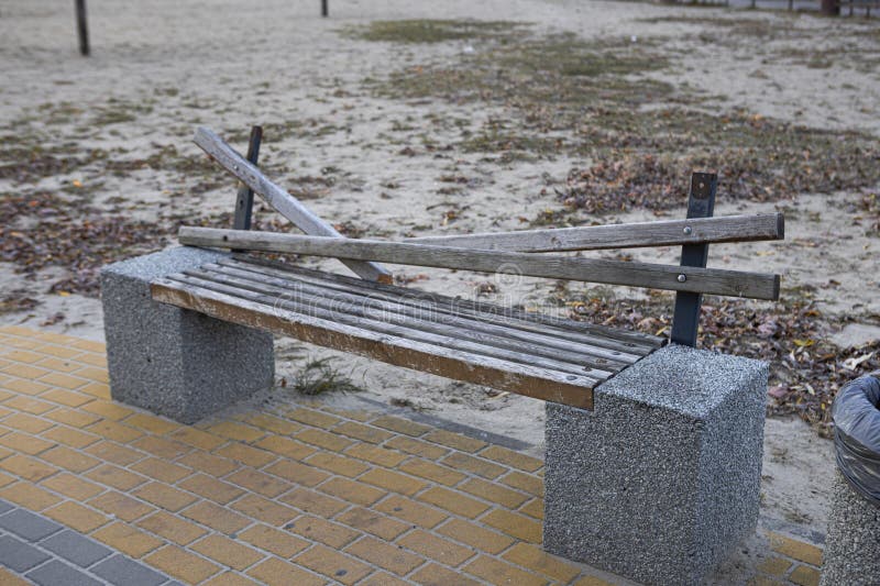 A broken wooden bench stands on a brick path stock photos