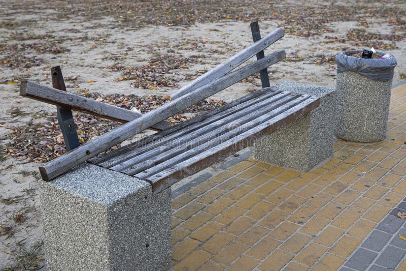 A broken wooden bench stands on a brick path stock photos