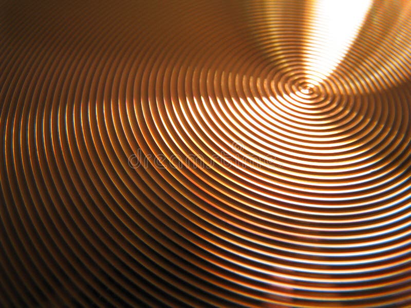 Photo of bronze copper gold circles vertigo pattern showing light being refracted from its textured surface. Photo of bronze copper gold circles vertigo pattern showing light being refracted from its textured surface.