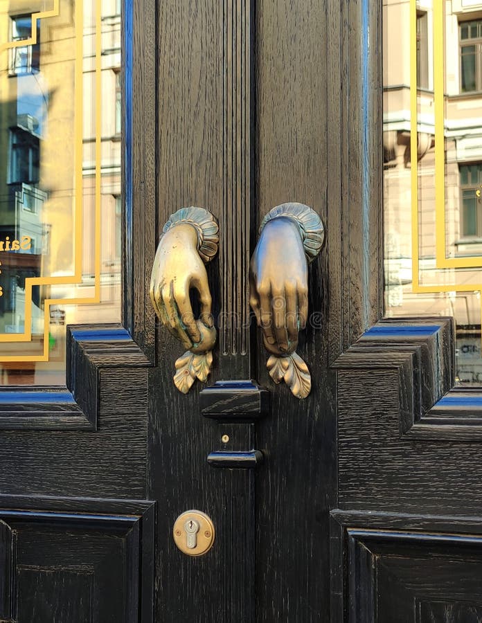 Bronze Door Handles in the Shape of the Hands on Black Wooden Door
