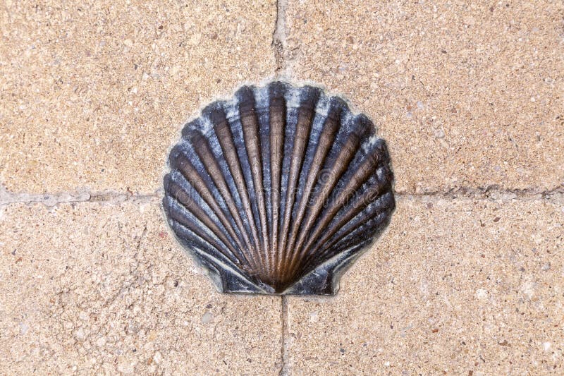 A bronze shell embedded in a textured stone pathway at a historic pilgrimage site stock images