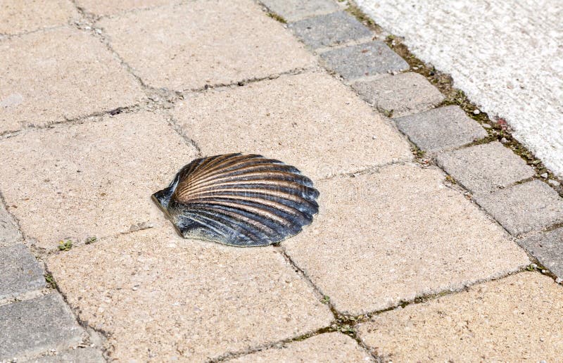 A bronze shell embedded in a textured stone pathway at a historic pilgrimage site stock photography