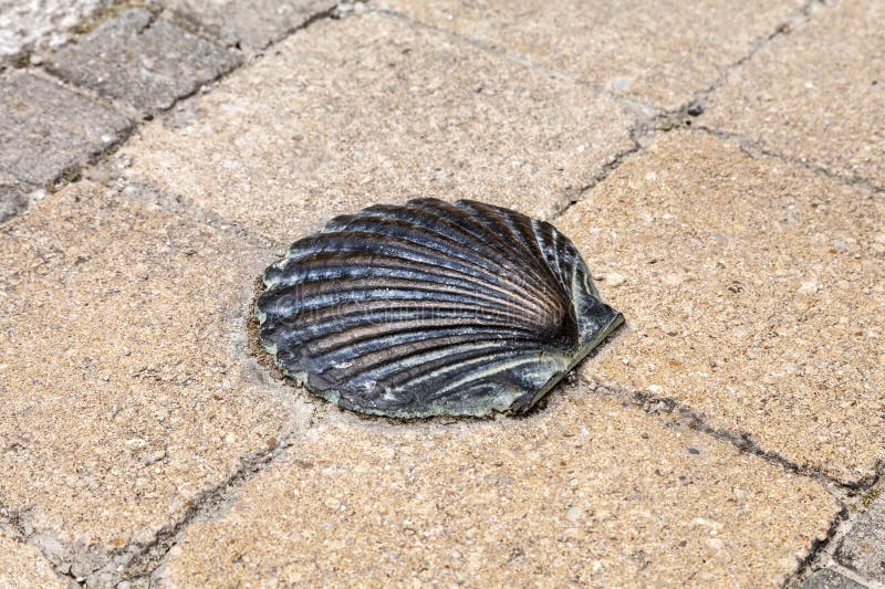 A bronze shell embedded in a textured stone pathway at a historic pilgrimage site stock photo