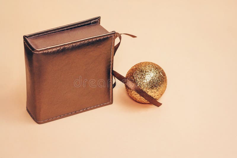 Bronzefarbiger Präsentkarton des Retrostils mit einem Seidenbogen allein mit Goldfunkelndem Weihnachtsball auf Pastellhintergrund stockfoto Bronzefarbiger Präsentkarton des Retrostils mit einem Seidenbogen allein mit Goldfunkelndem Weihnachtsball auf Pastellhintergrund stockfoto