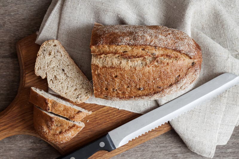 Brood van geheel tarwebrood met plakken op houten raad op keukenlijst royalty-vrije stock foto Brood van geheel tarwebrood met plakken op houten raad op keukenlijst royalty-vrije stock foto