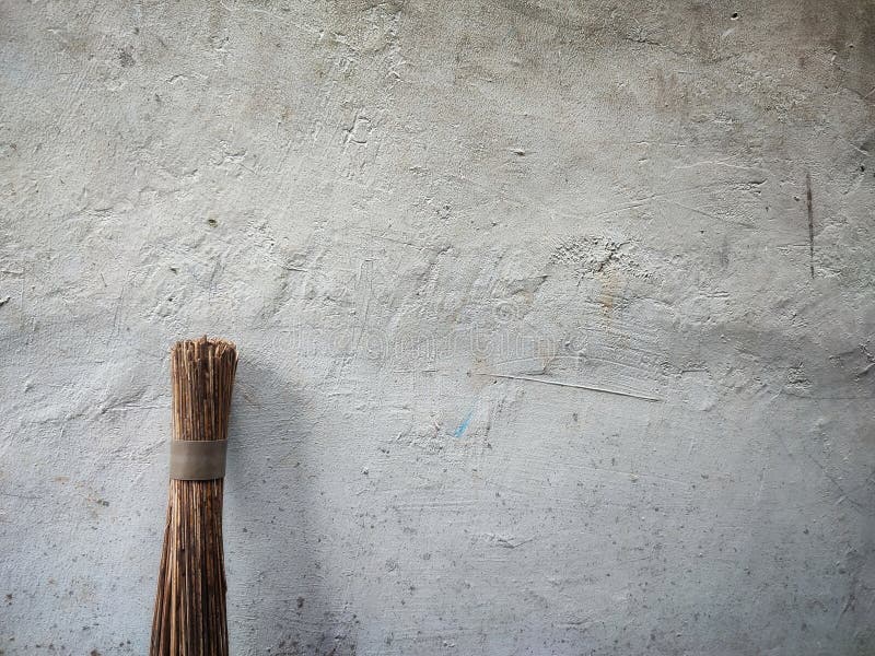 A broom stick propped against gray rough textured wall creates simple and minimalist composition royalty-vrije stock afbeelding