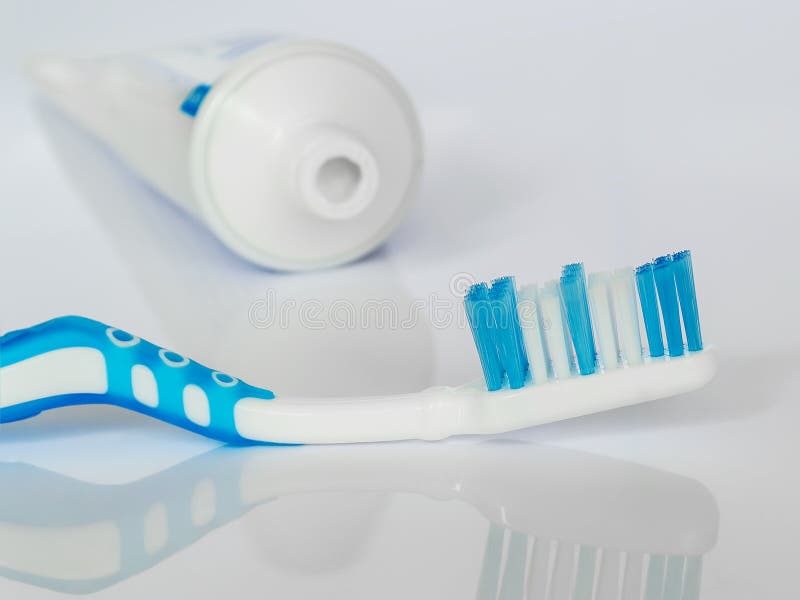 Blue toothbrush on a white glossy background. The concept of daily dental care, oral hygiene, prevention of diseases of the teeth and gums, health care. Blue toothbrush on a white glossy background. The concept of daily dental care, oral hygiene, prevention of diseases of the teeth and gums, health care