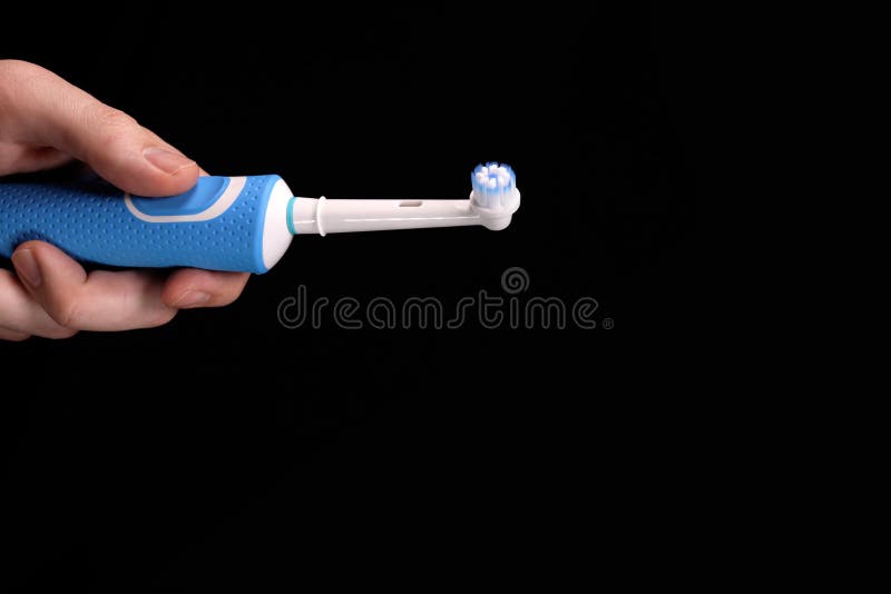Brosse à dents électrique moderne à main sur fond noir concept d'hygiène buccodentaire. espace de copie pour le texte