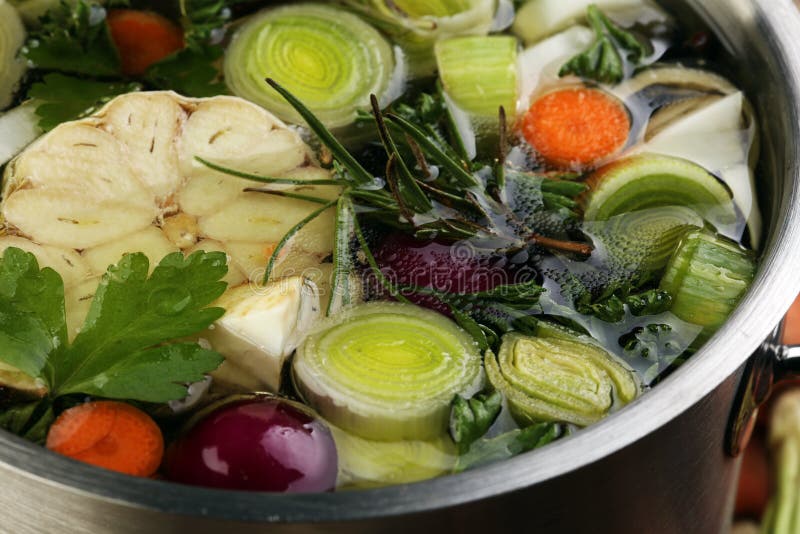 Broth with carrots, onions various fresh vegetables in a pot - c