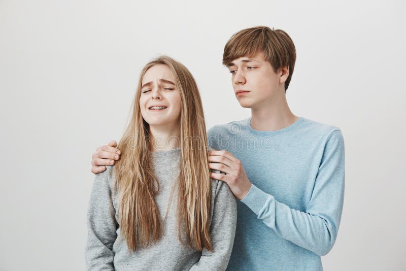 Brother estará siempre allí para la hermana Dos hermanos que se colocan sobre la pared gris después de noticias impactantes de la foto de archivo Brother estará siempre allí para la hermana Dos hermanos que se colocan sobre la pared gris después de noticias impactantes de la foto de archivo