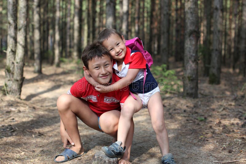 Brother huging each other outdoor, smiling , 10 and 4 years