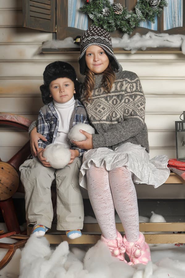 Brother and sister on a bench in front of the house in winter