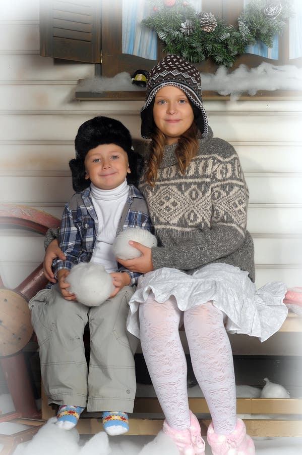 Brother and sister on a bench in front of the house in winter